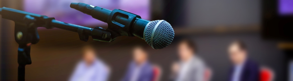 Four speakers on a stage in front of a microphone