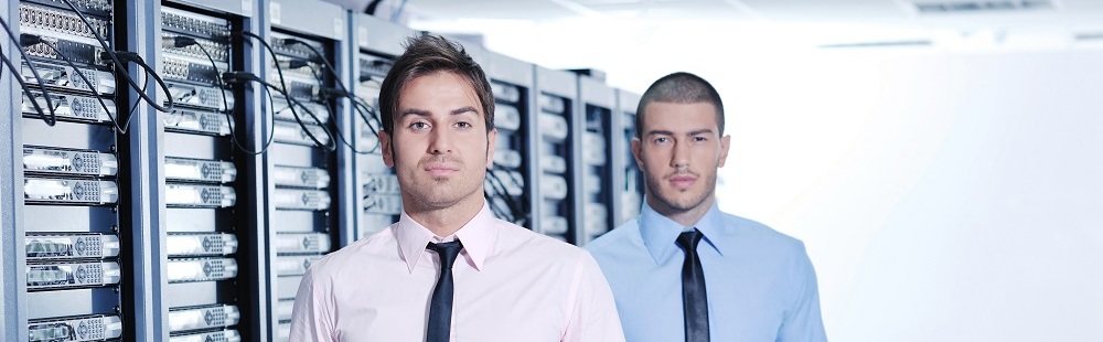 Two IT guys standing in front of a row of servers